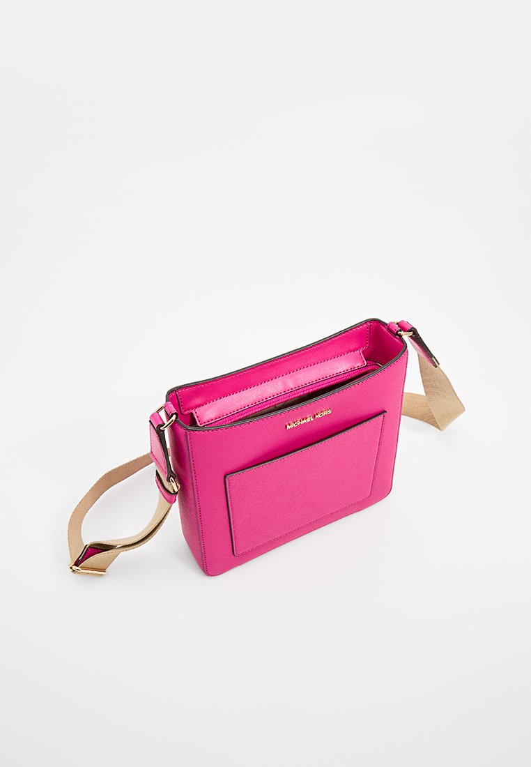 Roze synthetische crossbody tas met een gouden logo, een zipsluiting en een voorvak. Voorzien van een tan schouderband en contrasterende zwarte afwerking.