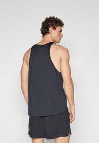 Débardeur noir pour homme en tissu léger et respirant, avec un col rond et un dos nageur, associé à un short noir.