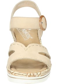 Sandale en cuir beige avec deux découpes, sangle réglable avec boucle circulaire marron, semelle texturée avec un motif tissé.