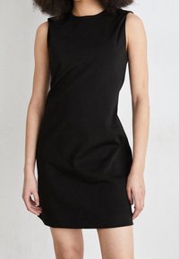 Svart ärmlös klänning i smidigt, elastiskt material. Fitted modell med rund halsringning och minimala sömmar. Enkel och elegant design.