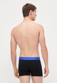 Schwarze Boxershorts mit einem blauen Bund, aus weichem Stoff, mit eng anliegendem Schnitt und minimalistischer Gestaltung, zeigt die Rückansicht.