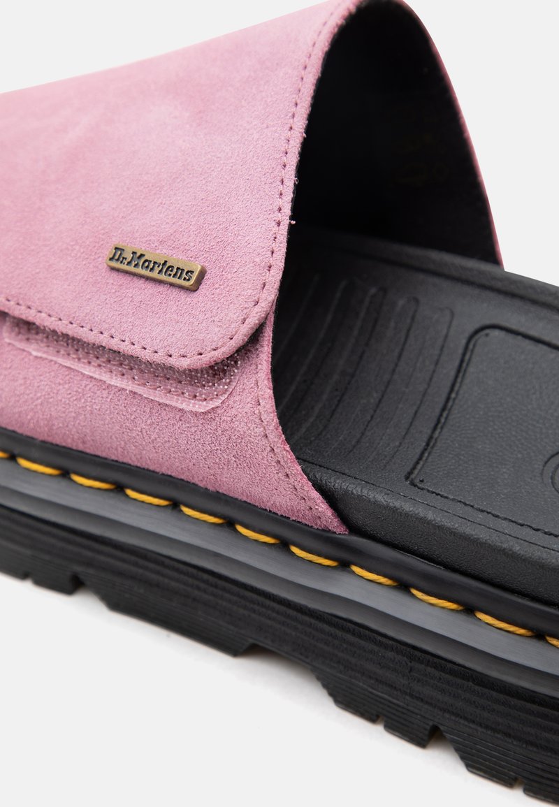 Nahaufnahme einer rosa Wildleder-Dr.-Martens-Pantolette mit schwarzer, strukturierter Sohle und gelber Ziernaht.