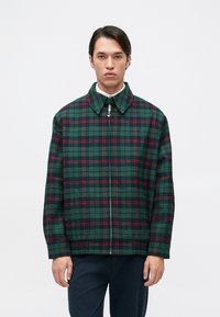 Πράσινο και ναυτικό καρό μπουφάν με κόκκινες λεπτομέρειες, διαθέτει γιακά, μπροστινό φερμουάρ και μακριά μανίκια. Υφασμάτινη υφή με άνετη εφαρμογή.