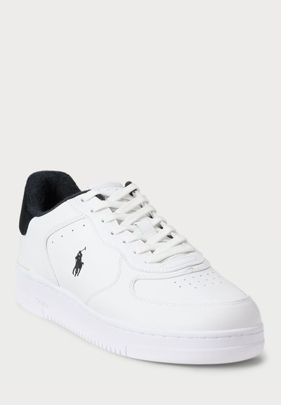 White leather sneaker with black suede accents, perforated toe, and white rubber sole. Features flat laces and a logo on the side.