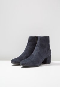 Dunkelblaue Wildleder-Stiefeletten mit strukturiertem Finish, spitzer Zehenpartie und blockhohem Absatz. Mit einem seitlichen Reißverschluss für leichtes An- und Ausziehen.