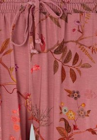 Pink fabric with floral and leafy botanical patterns in shades of brown, yellow, purple, and orange, featuring a tied drawstring waist.