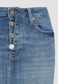 Jupe en denim bleu avec fermeture à boutons sur le devant et une poche avant, ornée de boutons en métal argenté et de coutures jaunes.