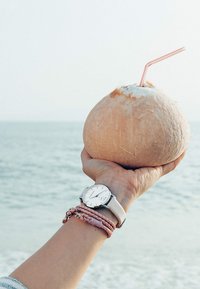 K coco s slamkom u ruci, s glatkom bež površinom i svijetlosmešavim vlaknima, uz srebrni sat i roza narukvice.