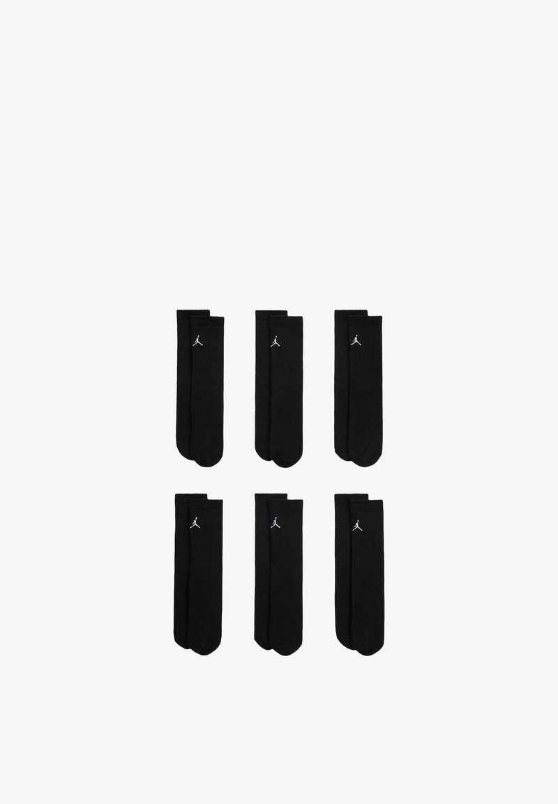 Chaussettes noires à texture côtelée, avec un petit logo Jordan blanc près du haut. Six paires empilées de manière uniforme.