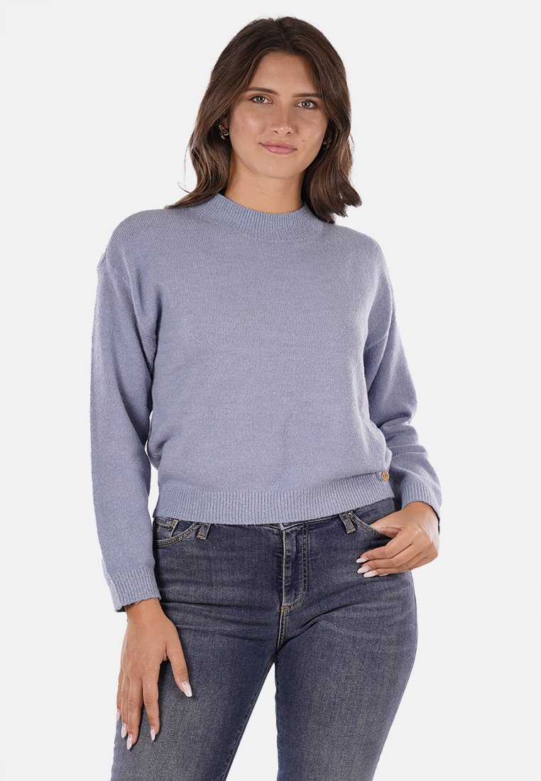 Maglione azzurro chiaro a maglia con scollatura rotonda e orlo a coste, abbinato a jeans in denim scuri. Il tessuto sembra morbido e leggermente testurizzato.