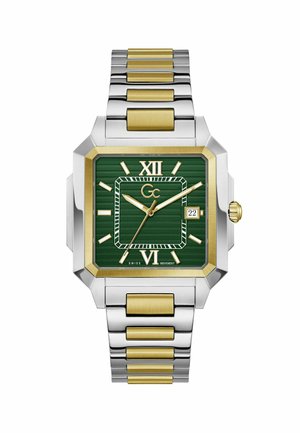 Négyzet alakú kétszínű ezüst és arany fémóra zöld számlappal, arany római számokkal, dátumablakkal 3 óránál és három arany mutatóval.