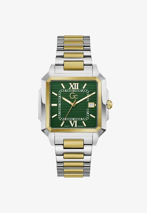 Kwadratowy, dwukolorowy zegarek z metalu w odcieniach srebra i złota, z zieloną tarczą, złotymi rzymskimi cyframi, okienkiem daty na godzinie 3 oraz trzema złotymi wskazówkami.