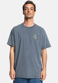 Gray cotton t-shirt with a relaxed fit, featuring a colorful graphic print on the left chest and short sleeves. Simple, unembellished design.
