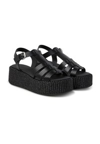 Sandali platform neri con texture intrecciata, dotati di fasce incrociate e fibbie alla caviglia. Il materiale appare sintetico o simile alla pelle.