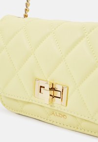 Borsa a tracolla in pelle giallo chiara trapuntata con chiusura e catena in tonalità oro; presenta una superficie liscia e dettagli di cucitura discreti.