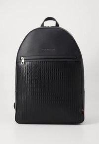 Černý batoh s texturovaným povrchem, vybavený přední kapsou na zip, logem a zaobleným horním tvarem.
