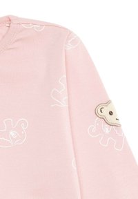 Camiseta de manga larga rosa fabricada con un tejido suave, con patrones de elefantes blancos y un parche texturizado de oso crema en el hombro izquierdo.