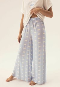 Jasnoniebieskie spodnie z szerokimi nogawkami w białe wzory chmur; miękka tkanina; elastyczny pas; luźny krój; zestawione z luźną białą koszulką.