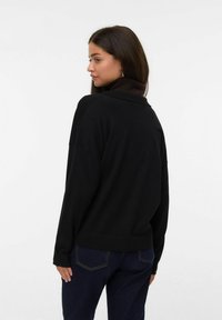 Svart sweatshirt med krage, med sänkta axlar och ribbade muddar. Materialet verkar mjukt och har en avslappnad passform.