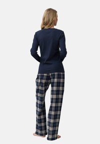 Top de manga larga azul marino con cuello redondo combinado con pantalones de cuadros en azul claro y crema; tejido mezcla de algodón, corte relajado y piernas rectas.