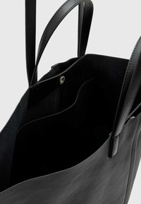 Juodos odos didelė rankinė su dviem petnešomis, minkštu vidumi, magnetiniu užsegimu ir keliais vidiniais skyreliais organizavimui.