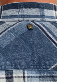 Camicetta a quadri con colori blu, bianco e navy. Tessuto testurizzato con un'etichetta PME LEGEND visibile sul colletto posteriore.