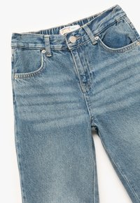 Jeans azules de mezclilla para niños con un diseño clásico de cinco bolsillos, pierna recta, lavado claro y costuras en contraste. Presenta un cierre de botón metálico.