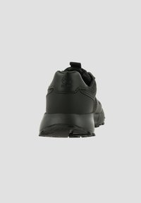 Svart atletisk sko med en texturerad ovandel, vadderad krage och gummisulor med mönster. Bakifrån syns logotypen på hälen.