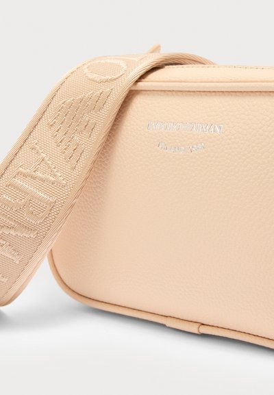 Μπεζ τσαντάκι ώμου από δερματίνη με φαρδιά τιράντα που φέρει ανάγλυφο κείμενο "Armani" και ασημί λογότυπο "Emporio Armani Milano 1981".