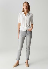 Chemise blanche à manches courtes avec un col, jeans gris slim-fit et chaussures slip-on beige clair. Design simple, texture lisse et détails en boutons.