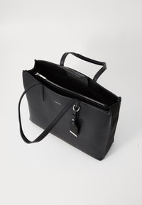 Black leather tote bag with a zip closure, double handles, and a detachable charm. Features a smooth surface and structured design with interior compartments.