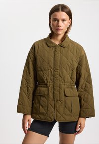 Olivgrüne gesteppte Jacke mit Kragen und tailliertem Schnitt, ausgestattet mit zwei aufgesetzten Fronttaschen. Glatte Textur und leicht.