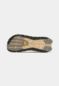 Semelle Vibram avec des crampons multidirectionnels pour une meilleure adhérence. Dispose d'une combinaison de couleurs beige et vert foncé, d'une surface texturée et de bords bien définis.