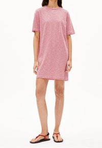 Czerwona i biała, paskowana sukienka koszulowa z krótkimi rękawami i okrągłym dekoltem, wykonana z miękkiego materiału, sięgająca nad kolano. Noszona z czarnymi sandałami.