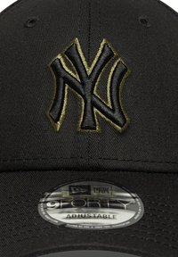Căciulă ajustabilă neagră cu un logo brodat, ridicat, în aur și negru, reprezentând "NY". Include o etichetă gri New Era 9FORTY pe soare.