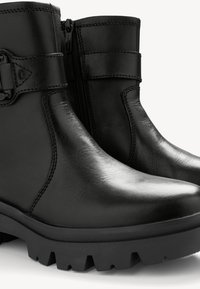 Stivaletti neri alla caviglia realizzati in pelle liscia, con zip laterale, dettaglio della cintura regolabile e suola in gomma robusta e texture.
