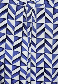 Bavlněná tkanina s geometrickým vzorem modrých a bílých šípů. Obsahuje skládací výstřih pro zvýšení textury a detailu.