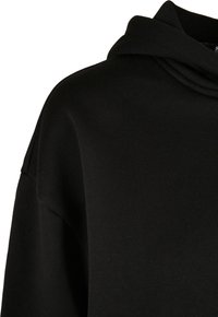 Sudadera negra con capucha de textura suave, con un corte relajado y diseño de cuello doblado. Sin patrones visibles ni detalles de hardware.