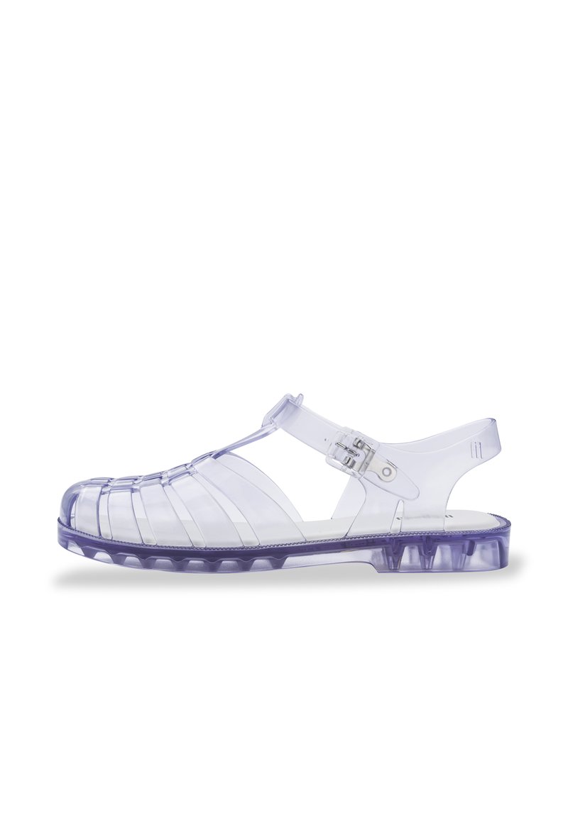 Sandalias de plástico morado transparente con punta cerrada, parte trasera abierta y correa ajustable. Presentan cortes horizontales y verticales.