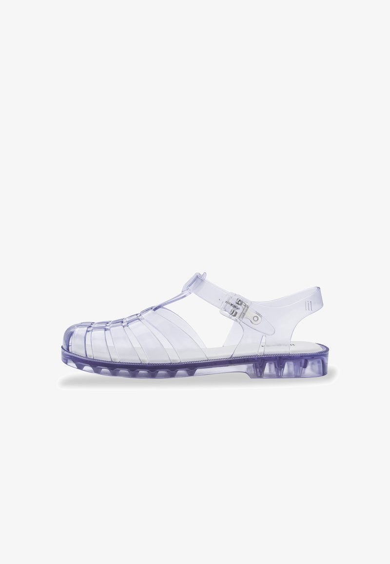 Sandalias de plástico morado transparente con punta cerrada, parte trasera abierta y correa ajustable. Presentan cortes horizontales y verticales.
