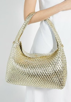 Gouden handtas van geweven materiaal met een gladde textuur, een afgeronde vorm en een gevlochten hengsel, met een subtiele glans en een elegante oversized uitstraling.