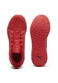 Baskets de sport rouges avec tige en maille, fermeture à lacets, languette rembourrée et semelle en caoutchouc texturée présentant des motifs circulaires et des accents de marque.
