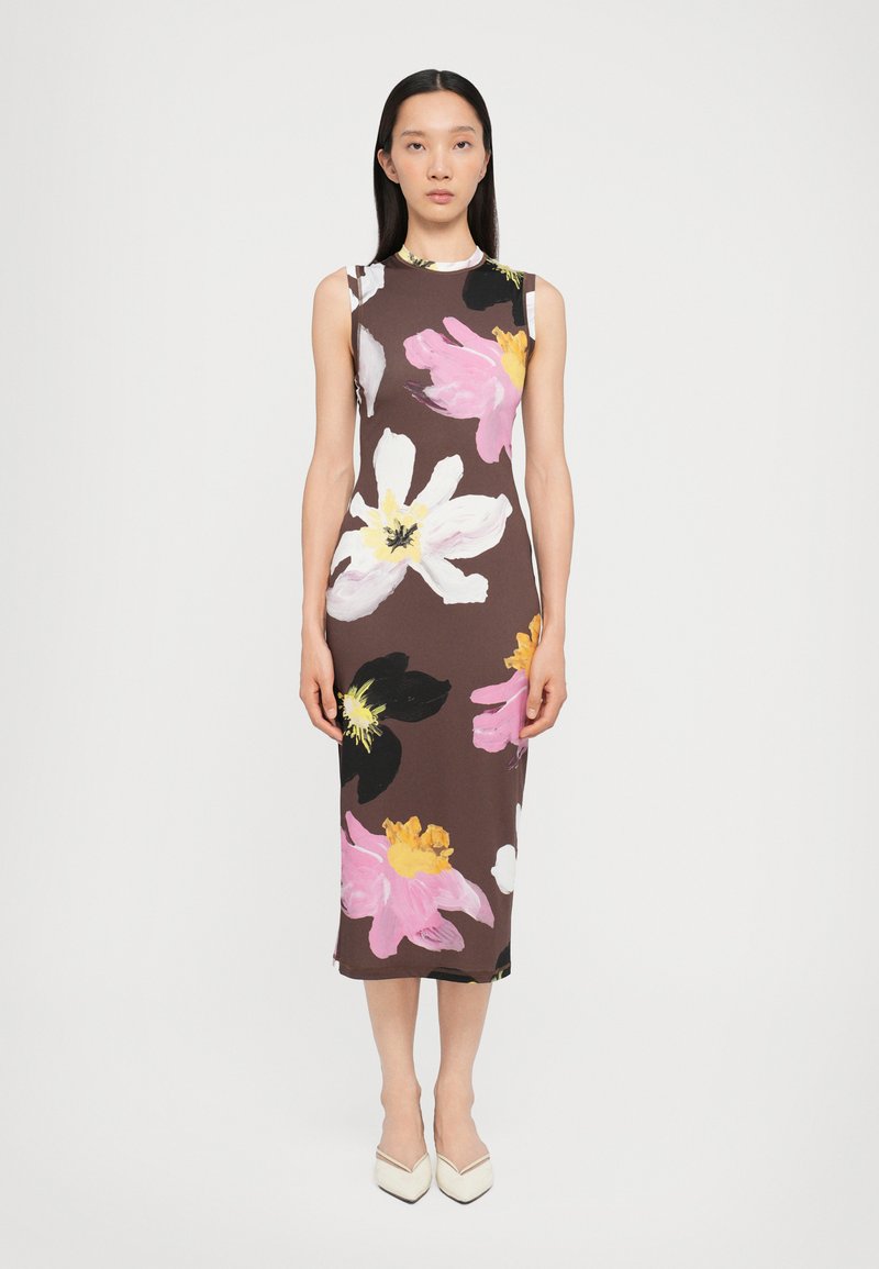 Primary brown sleeveless dress with large pink, white, and yellow floral patterns; fitted design, knee-length, soft fabric, paired with white heels.