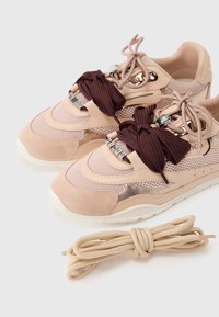 Baskets en maille rose et suède avec des lacets en tricot marron, des accents métalliques et une semelle en caoutchouc blanche. Comprend un lacet beige de rechange.