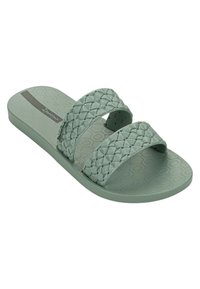 Sandali slip-on verde chiaro con due cinturini intrecciati, suola texturizzata e accenti di glitter sottili. Realizzati in un materiale flessibile e durevole.