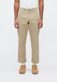 Beige cotton trousers with a straight cut, flat front, and two side pockets. Features a single button closure and belt loops.