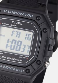 Digital wristwatch with black plastic casing and textured rubber strap. Features a rectangular display with white backlight, 50m water resistance.