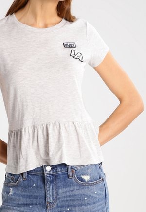 Top grigio a maniche corte con orlo peplum, caratterizzato da toppe ricamate "PARADISE LA". Realizzato in un tessuto morbido con vestibilità casual.