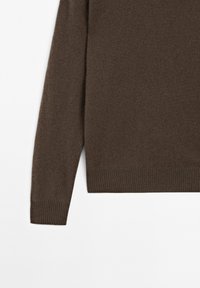 Pull en tricot marron avec une texture douce, doté d'un ourlet et de poignets côtelés. Le design comprend une coupe ample et des manches longues.