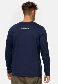 Camisa de manga larga en color navy con cuello redondo y texto blanco "WEAR THE CODE" en la parte posterior. Confeccionada en una tela suave y elástica con una textura suave.